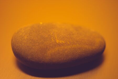 One big pebble stone on the table, orange light