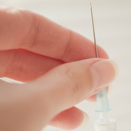 syringe in female hand, macro photo with selective focus.の写真素材