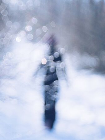 Walk through the winter forest. Silhouette of a lonely person in black walking on the road
