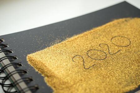 Black notebook covered with goldenequins, inscription 2020の写真素材
