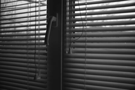Window with half closed blinds in dark room. Jalousie background. Black and white photoの写真素材