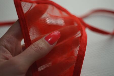 Red transparent panties in a female hand with red manicure.の写真素材