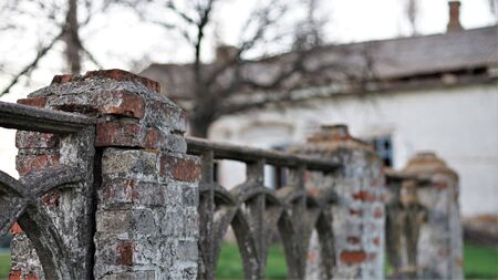 Old stone fence, in the background of an abandoned brick houseの写真素材