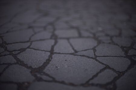 Old road surface made of old asphalt with cracks. Stone texture.の写真素材
