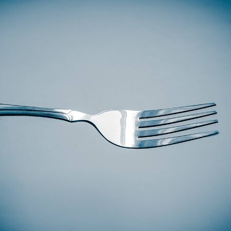 Shiny silver fork close-up in blue space.
