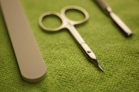 Set of tools for manicure on the green table. Scissors, nail file, cuticle shovel
