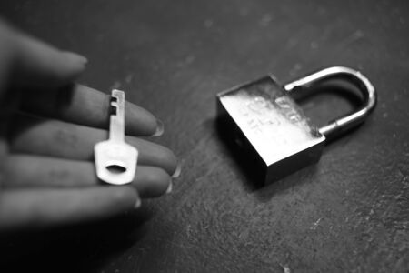 Metal open heavy lock on the table and female fingers with keyの写真素材