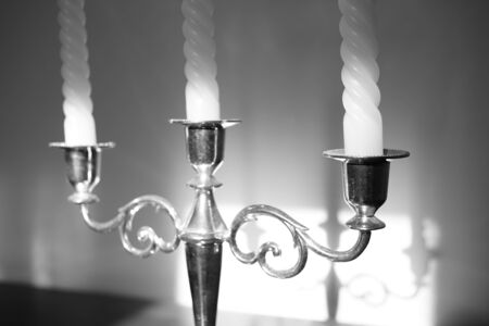 Candlestick with three candles. Shadow reflection on the wall. Black and white photo