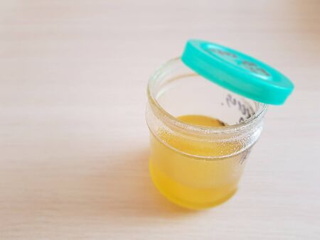 Open glass jar with honey on a wooden tableの写真素材