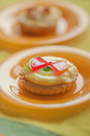 Sweet round cake with cream and red jelly watermelon slices in orange plate on the tableの写真素材
