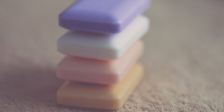 Stack of four bars of soap different colors on a brown towelの写真素材