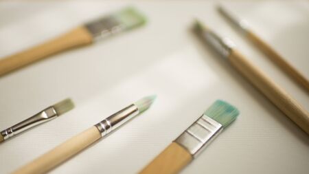 Different brushes with wooden handles on white textured paper.の写真素材