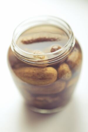 Pickled cucumbers in open jar on the white table.の写真素材