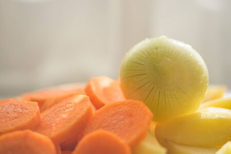 Raw onion and round slices of carrots and potatoes close-up. Healthy vegan food.