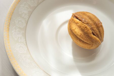 cookie walnut on a white saucer and a sunny table.の写真素材