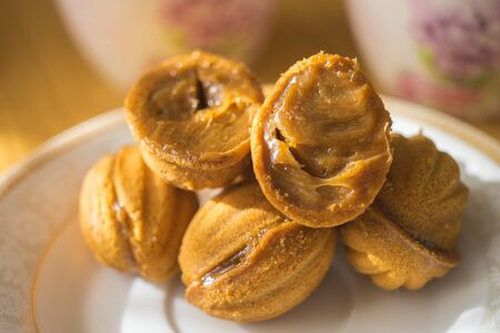 Walnut shaped cookies with condensed milk in white saucer. One open in half. Sweets on the sunny...