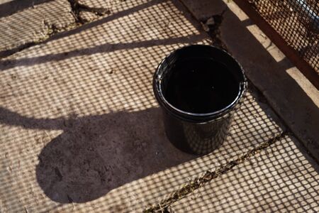 Plastic bucket on an old stone floor. Shadows from the mesh fence.の写真素材