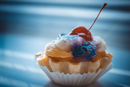 Cake basket with fruits and cherry on the dark blue table. Side viewの写真素材