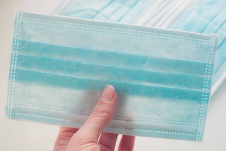 Blue medical face mask in female hand closeup