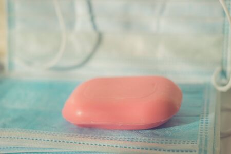 Pink bar of soap on blue medical masks in the bathroom. Side view, close upの写真素材