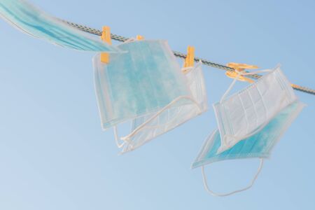 Medical face masks hang on a clothesline in blue sky background