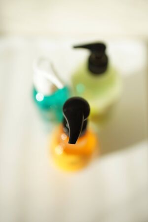 Orange, lime and green bottles with dispensers on a white table, beautiful selective focus, top viewの写真素材