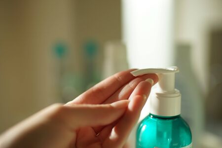 A female finger presses on a disinfectant gel in a small plastic bottle on the other hand.の写真素材