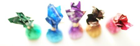 Chocolate candies in colorful wrappers, top view, blurred