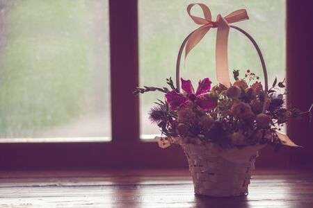 Cute basket with roses, flower arrangement on the windowsill, side view.の写真素材
