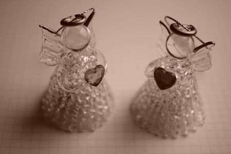 two small statue of an angel with a heart in his hands on a paper in a cage