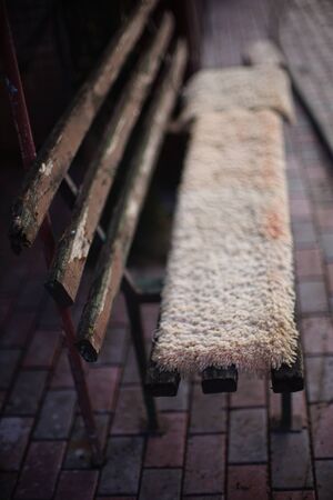 Old wooden bench with peeling paint covered with carpets.の写真素材