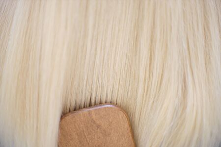 Lovely long blond hair combing with wooden massage comb close-up.の写真素材