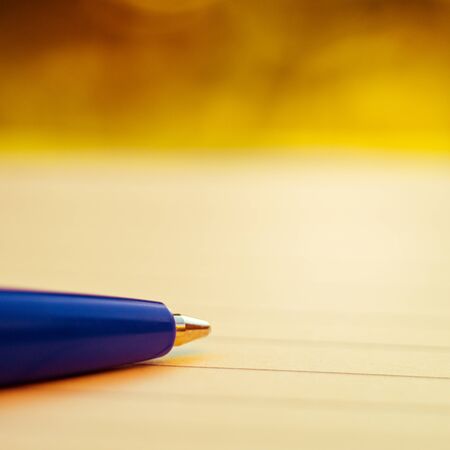 Blue ball pen on notebook paper in a line. Macro photo. Copy space