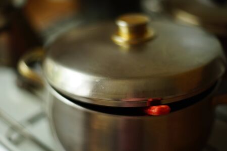 stainless steel pan with red soup ladle under the lid closeup on the stove.の写真素材