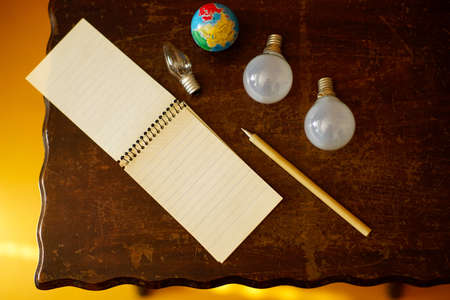 Open notebook, pen, globe and three light bulbs on a wooden table. View from above. Idea or inspiration concept.の写真素材