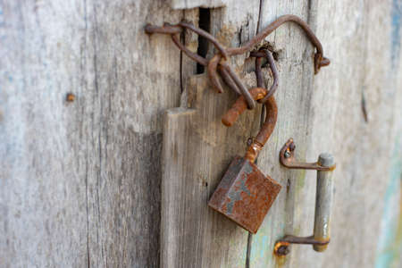 Old wooden door with rusty handle, hook and lock.の写真素材
