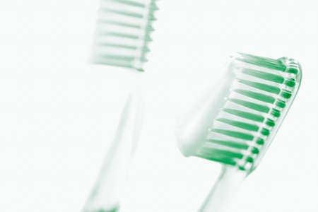 Two green plastic toothbrushes with toothpaste on white art backgroundの写真素材