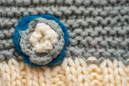 Knitted pattern of threads in two colors and styles. Small flower on a scarf