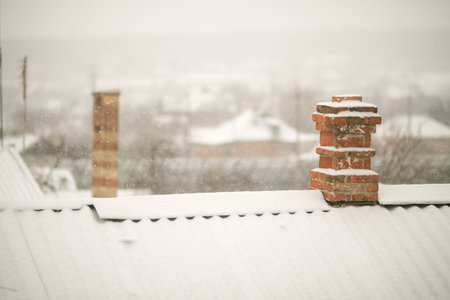 Rural landscape with old roofs and chimneys in the snow. Winter snowfall.
