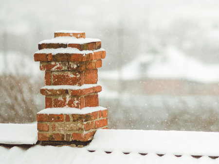 Old red brick chimney in the snow on the rural roof closeupの写真素材