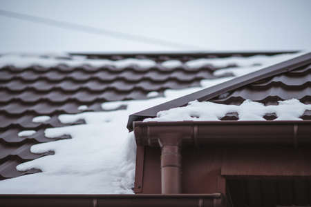 Closeup of brown tiled rooftop covered with snow in winter dayの写真素材