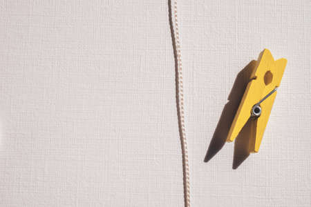 Yellow wooden clothespin and nylon thread on a white sunny table.の写真素材