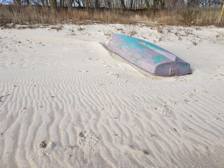 old metal boat with peeling paint on a sandy beach.