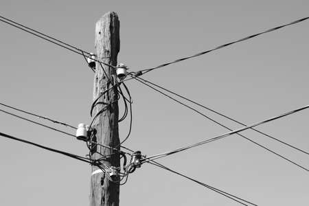old wooden pillar with wires in clear sky background