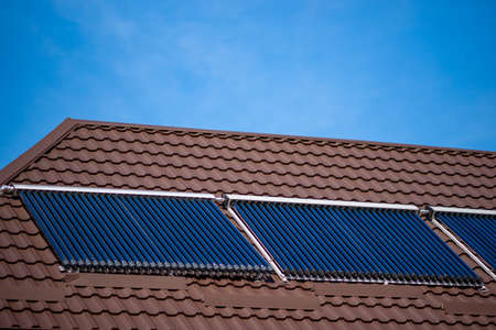 Solar cell tube on brown tiled roof in sunny day.の写真素材