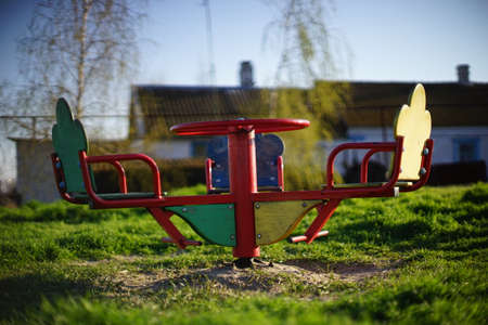 Outdoor playground with round carousel on the grass at spring sunset.の写真素材