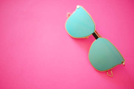 Blurred photo of blue sunglasses on a rich pink background. Copy spaceの写真素材