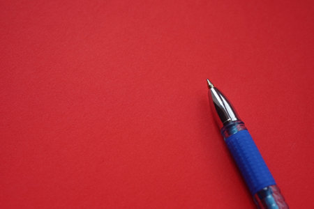 Blue ballpoint pen on red paper, copy space