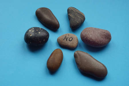 Pebble stones in flower shape with text no on main at blue table.の写真素材
