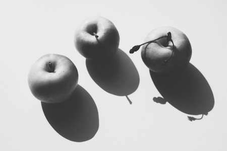 Three ripe apples on a white sunny table. BW photoの写真素材